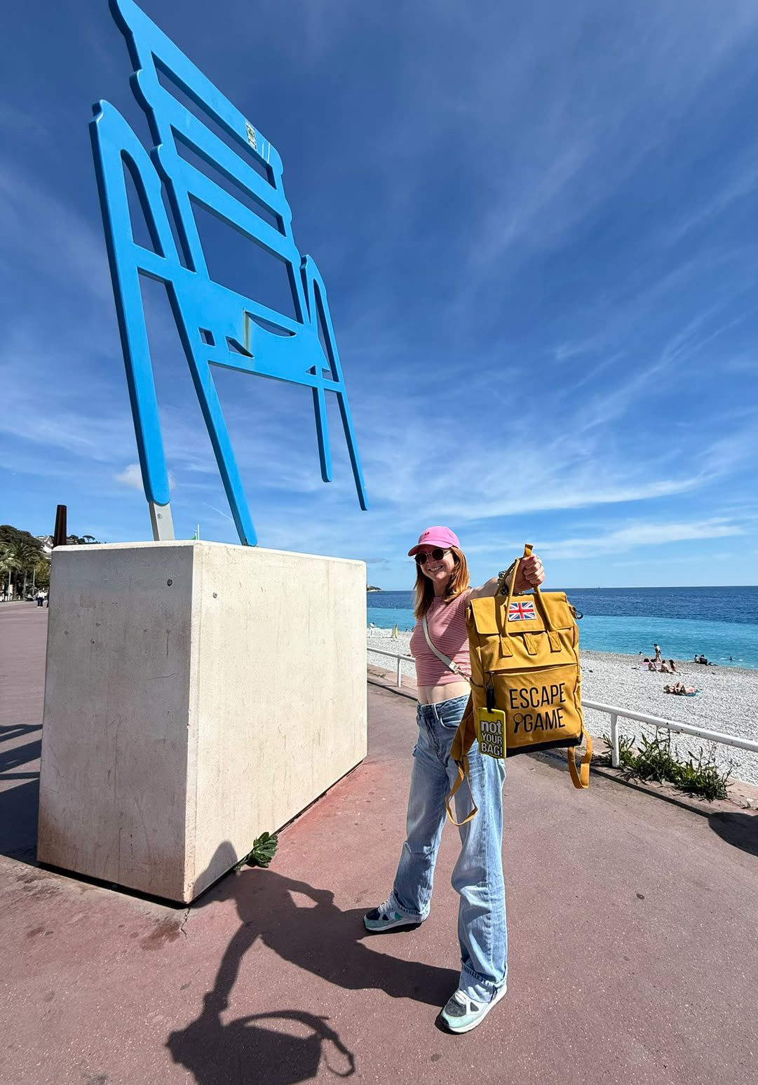 Tiffany, founder of Escape Nice, with the yellow game bag in front of the Chaise Bleue